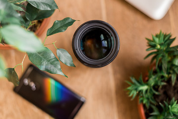 flat lay. laptop, cell phone, lens, flower stand on a wooden background. top view