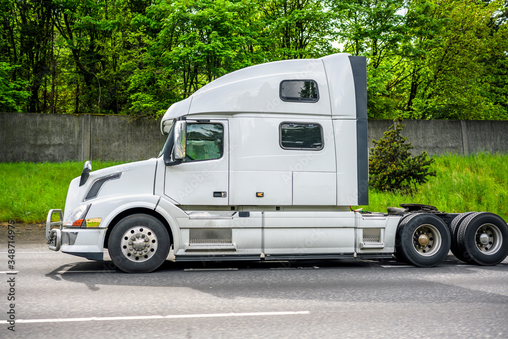Powerful big rig semi truck tractor running on the road with fence and ...