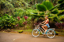 A Young Girl Riding Her Bicycle On A Rural Road In A Tropical Area Of Kauai In Hawaii. 