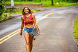 © Adam Hester - A twenty something girl riding her skateboard in a tropical area of Kauai in Hawaii.