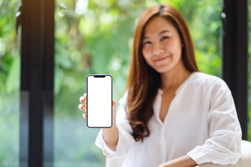 mockup image of a beautiful asian woman holding and showing a mobile phone with blank white screen ,