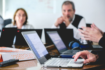 Wall Mural - Hand of a oldman businessman working on grey laptop computer in a business meeting with and oldmen and a old lady with glasses