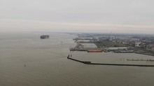 Aerial Panoramic View Over The Port And Seaside Of Cuxhaven With A Big Container Ship In The Distance On The North Sea