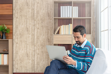 30s handsome businessman  searching and reading article from internet.  Modern arab businessman in casual clothes working at home.