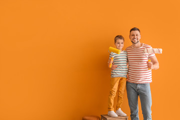 Wall Mural - Little son helping his father to paint wall at home