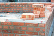 Building a brick foundation wall corner of a house construction using spirit level to keep the brickwork upright and level on a mortar bed.