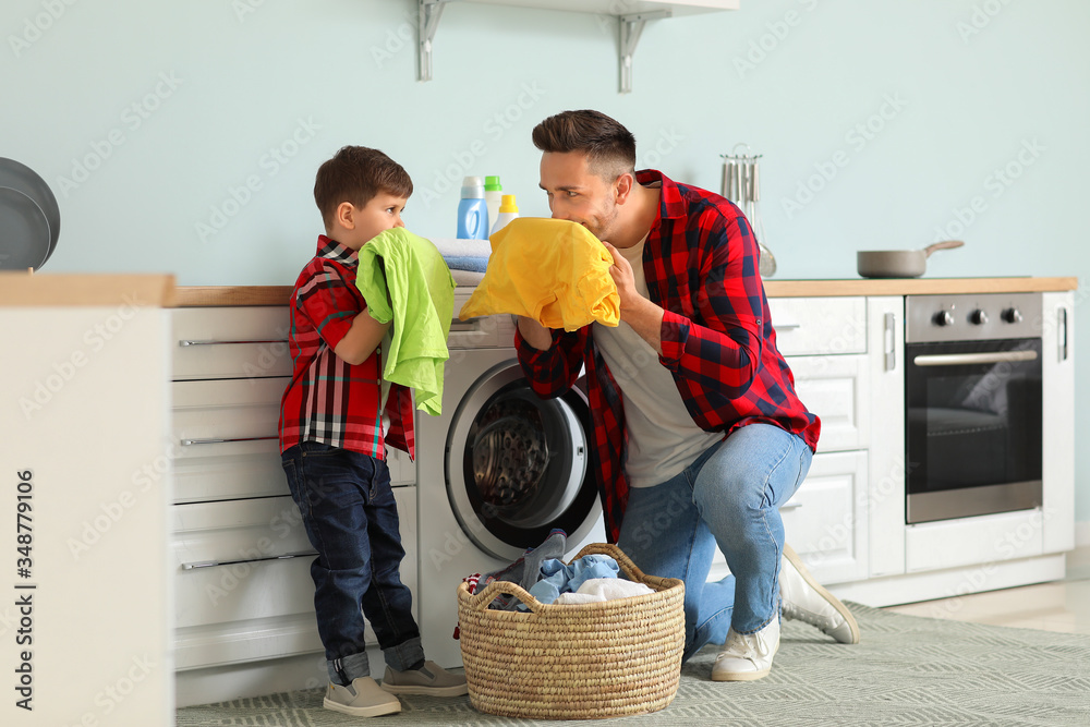 Man and his little son doing laundry at home