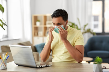 Canvas Print - quarantine, remote job and pandemic concept - happy indian man wearing face protective medical mask for protection from virus disease with laptop computer working at home office