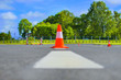 Traffic cone standing on dark asphalt. Orange cone in road works, parking area.Traffic cone on the airport runway. Cone fence posts on the road for car driving training at the driver training school.