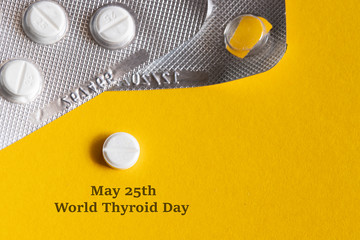 world thyroid day may 25 concept. thyroid hormone replacement therapy pills on yellow large backgrou