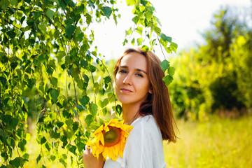 Beauty joyful teenage girl with sunflower enjoying nature and laughing on summer sunflower field. Sunflare, sunbeams, glow sun. Backlit