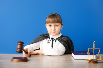 Sticker - Portrait of little judge sitting at table against color background