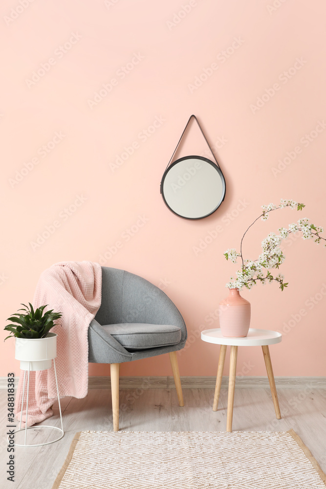 Interior of living room with stylish mirror and blooming tree branches - obrazy, fototapety, plakaty 