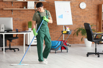 Canvas Print - Male janitor mopping floor in office