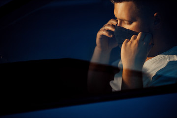 Attractive man driver in medical face mask inside the grey car, concept of coronavirus quarantine