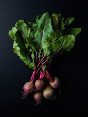 Bunch of beetroots on black background, from above