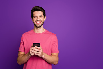Poster - Photo of handsome attractive guy young millennial hold telephone hands popular blogger addicted user wear casual pink t-shirt isolated purple color background