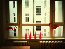 Red Bottles And Plastic Flamingos On Window Sill