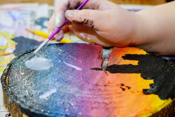 Girl uses colored paints brushes a picture in wooden