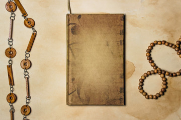 The concept of antiquity. Image for caption. Against the background of old paper lies a notebook and next to two wooden decorations.