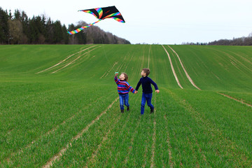 Children launch a kite in a field in spring