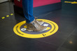 Closeup of feet of woman standing in the social distancing symbol on the floor in the train station during the Covid-19 pandemic