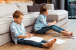 © LIGHTFIELD STUDIOS - cute siblings sitting on floor and drawing in living room