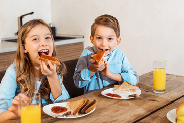 selective focus of happy siblings eating toast bread with bread