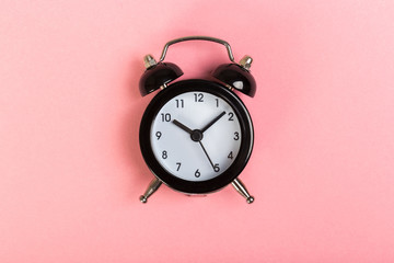 Wall Mural - black vintage alarm clock on a colored background, top view. concept of time, daily routine