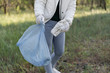© mtrlin - A woman collects trash in a bag. Cleaning the site of old bottles and plastic.