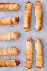 Sticker - Baked sausage rolls on the baking sheet on the wooden table. Hot dogs. Sausage in the dough.