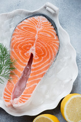 Wall Mural - Closeup of raw iced salmon steak with fresh dill and lemon, vertical shot, view from above