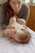 © soul kitchen - mother stands next to the child. Massage for the baby. Four month old baby smiling doing gymnastics