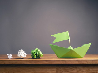 Wall Mural - New ideas or teamwork concept with crumpled paper and a green paper boat