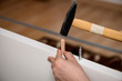Close up on hands hammering a wooden peg in furniture.