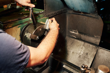 Professional machinist : man operating lathe grinding machine