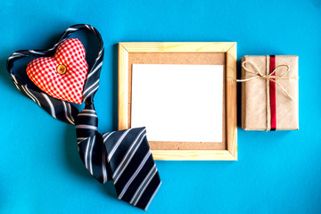 Stylish frame for an inscription on a blue background with a tie, a heart and a gift box. Congratulations on Father's Day June 19. Copy text.