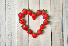 Top View Of Red Strawberries Forming A Heart On A White Wooden Table. Concept Of Love And Couple.