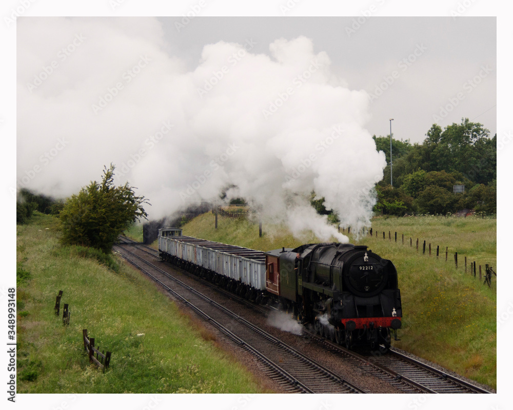Steam Train On Railroad Track Amidst Field Against Sky - obrazy, fototapety, plakaty 