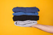 © ActionGP - Cropped photo of a man holding stack of folded clothes isolated on yellow background