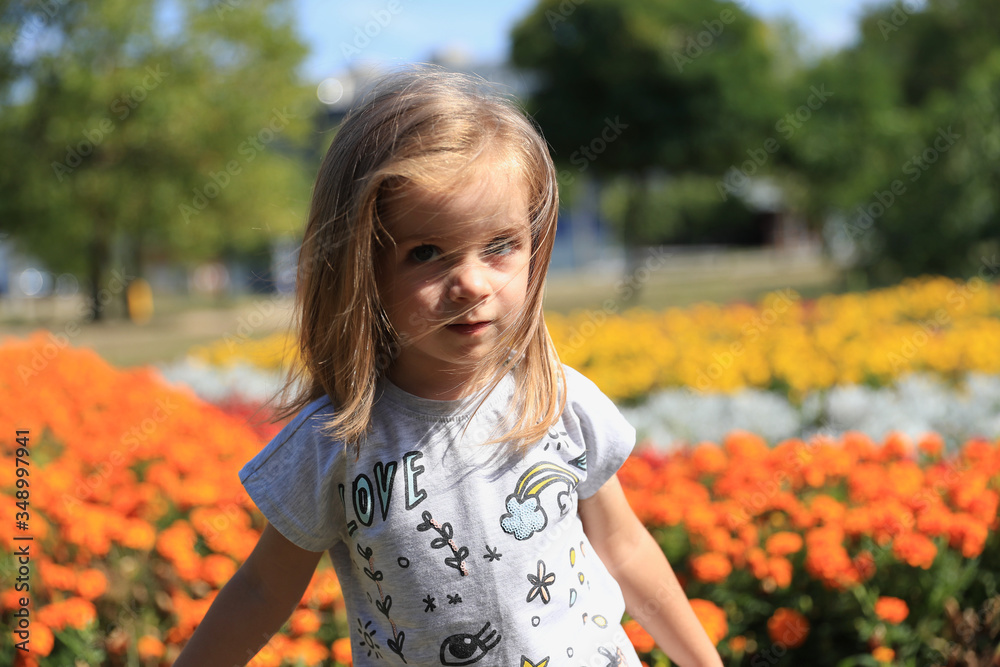 Mała dziewczynka na tle kwiatów - obrazy, fototapety, plakaty 