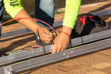 An Electrical Technician Attaches A Red Wire To The Framework That Will Hold Solar Panels With Zip Ties.
