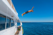 Fly after jump. Man jumping from yacht into blue sea water for dive. Summer fun lifestyle