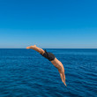 Fly after jump. Man jumping in blue sea water for dive. Summer fun lifestyle