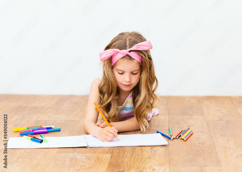 Little girl lying on the floor draws with pencils. Cute girl draws with ...