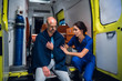 © Anna Kosolapova - Female paramedic talking to an injured man trying to comfort him, the man is sitting on the edge of an ambulance car in a blanket