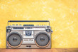 © BrAt82 - Retro outdated portable stereo boombox radio receiver with cassette recorder from circa 80s front concrete textured yellow wall background. Listening music concept. Vintage old style filtered photo