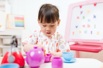 Wall Mural - toddler girl prerend play preparing tea party at home