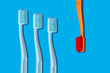 © Nicolle Clemetson - Modern Monochromatic Orange and Blue Toothbrushes Laying on Blue Background in Pattern