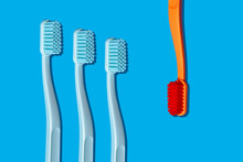 Modern Monochromatic Orange And Blue Toothbrushes Laying On Blue Background In Pattern